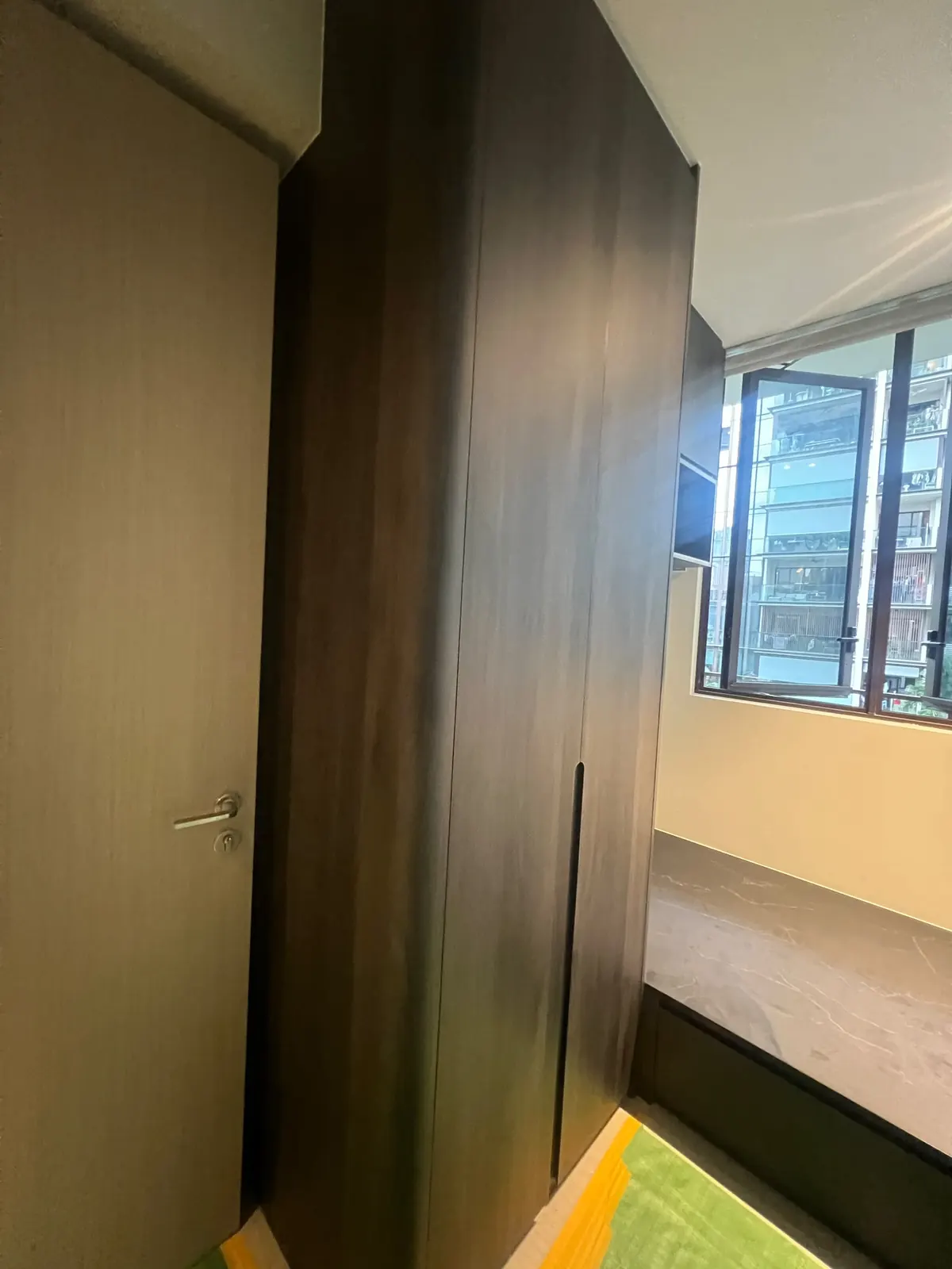 Full-height dark woodgrain wardrobe beside the bedroom door at Dairy Farm Residences